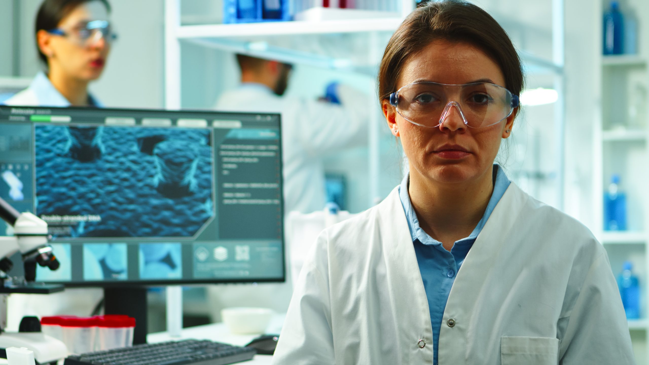 Investigadora en plano medio con una computadora de fondo